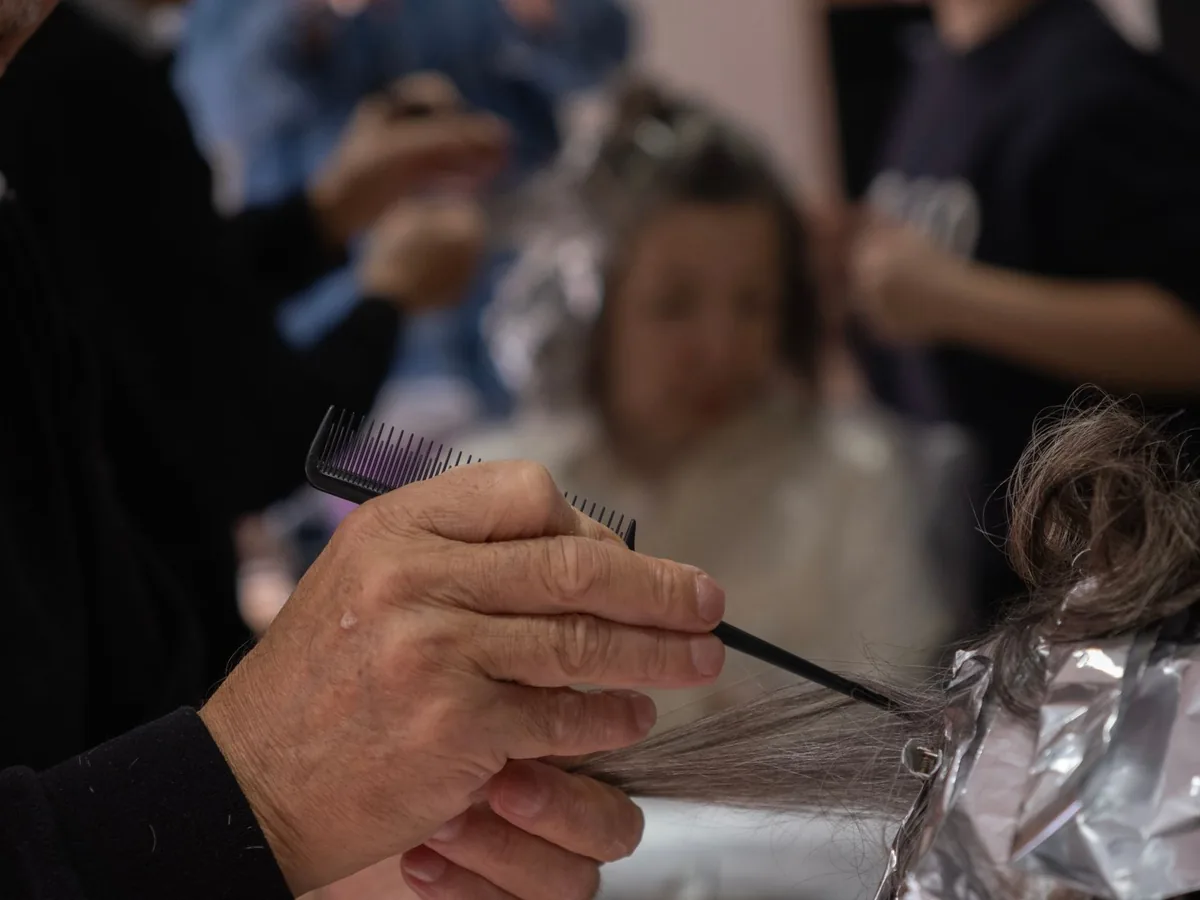 A hairdresser applies highlights to a client’s hair.