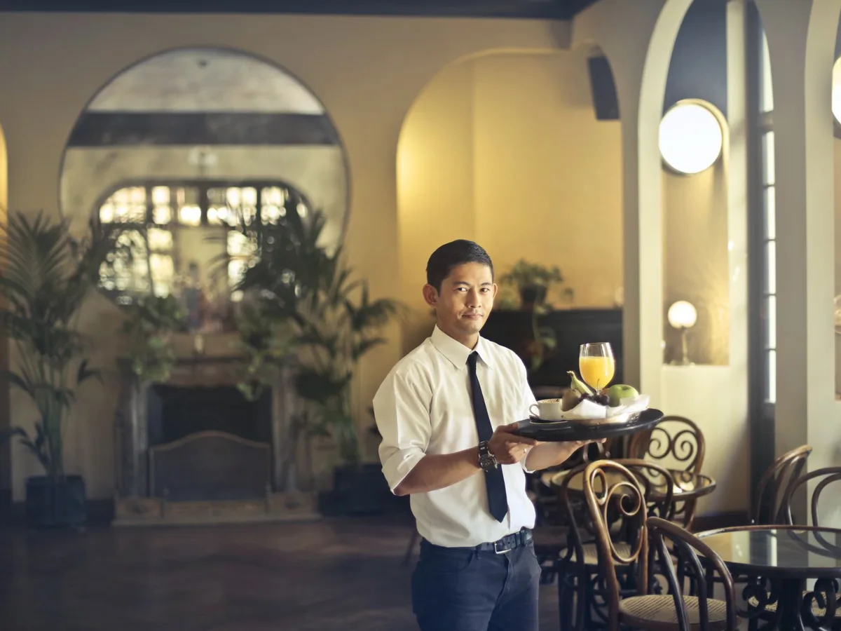 A waiter carries a tray through a restaurant.
