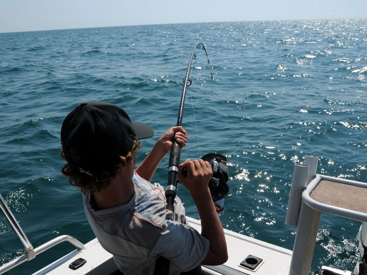 A man fishes from a boat on the water.