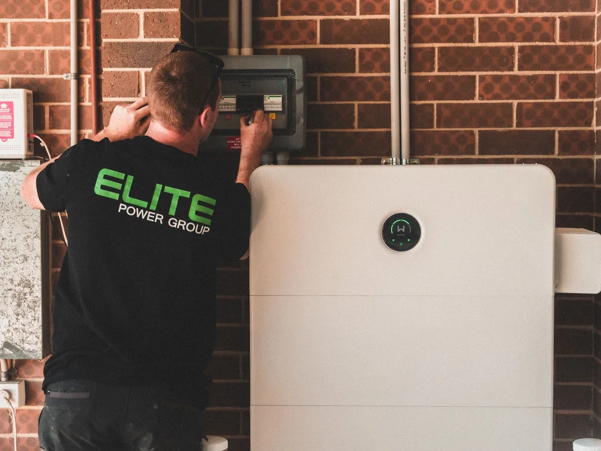 An electrician installs a residential battery storage system.