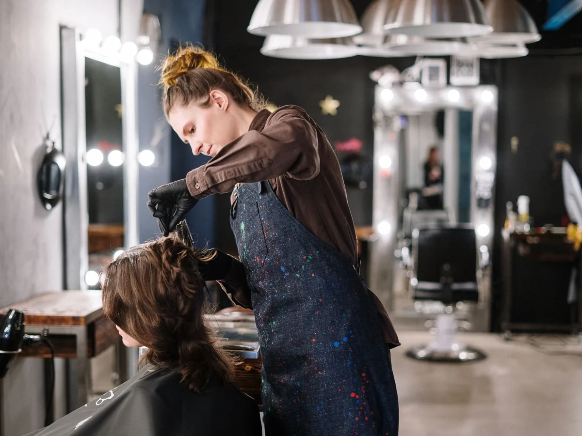 A woman has her hair cut in a salon.