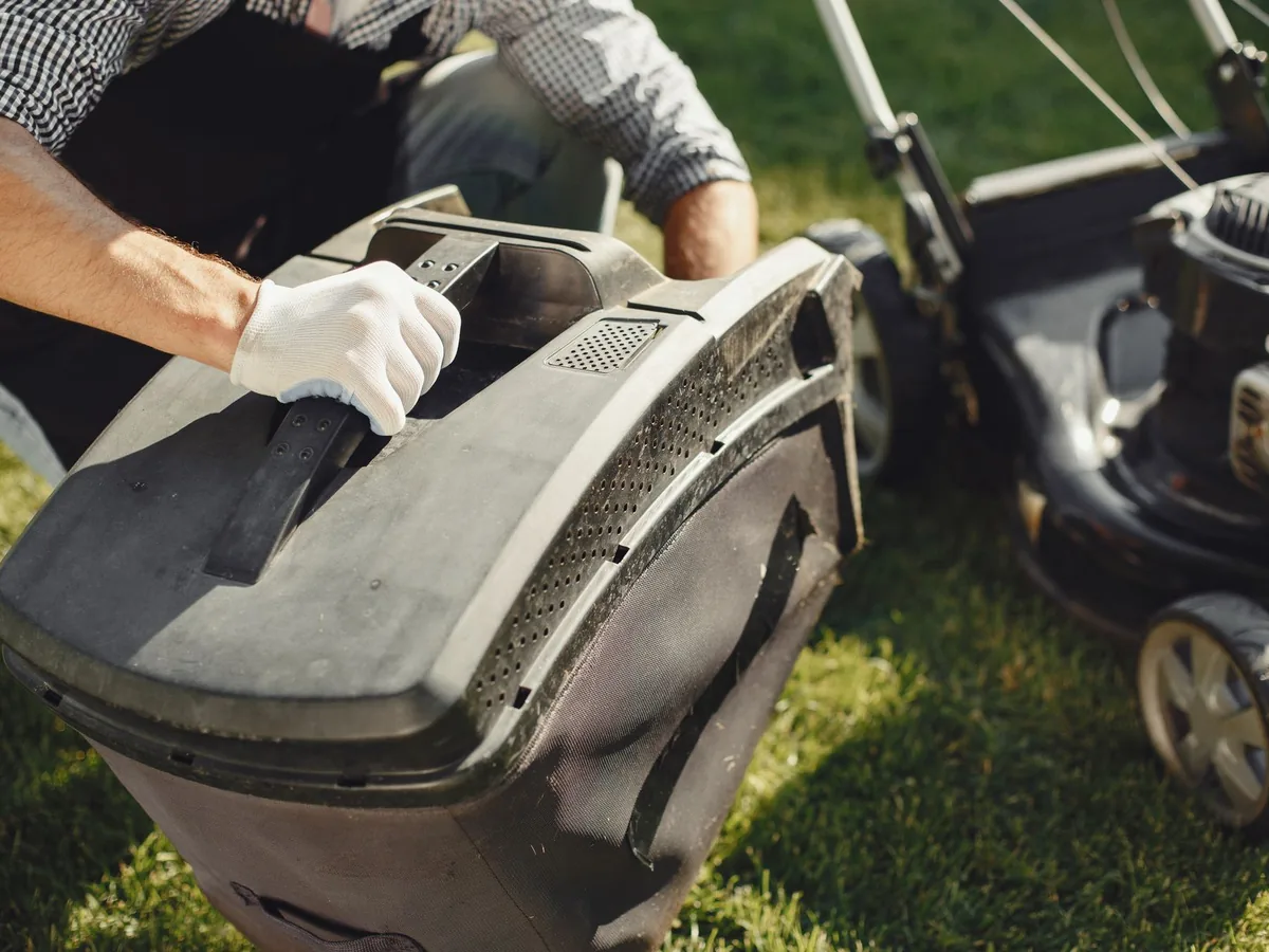 A gardener replaces the grass bag on a lawn mower.