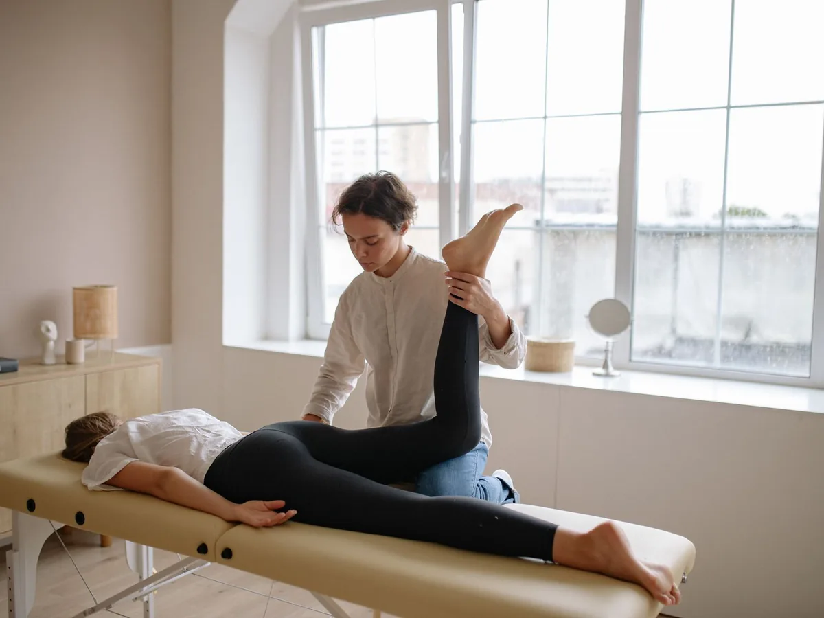 A therapist supports a client’s raised leg during treatment.